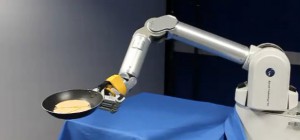 Le robot qui fait sauter les crêpes dans une poêle après apprentissage.
